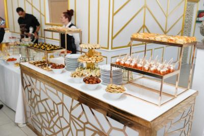 Table dressée avec une assiette blanche, un cadeau doré, une serviette beige nouée et des macarons en décoration.