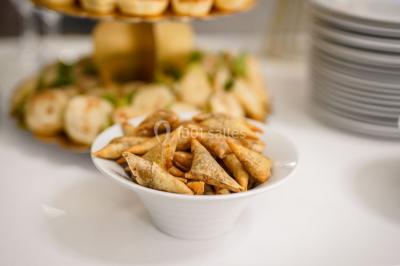Table dressée avec une assiette blanche, un cadeau doré, une serviette beige nouée et des macarons en décoration.