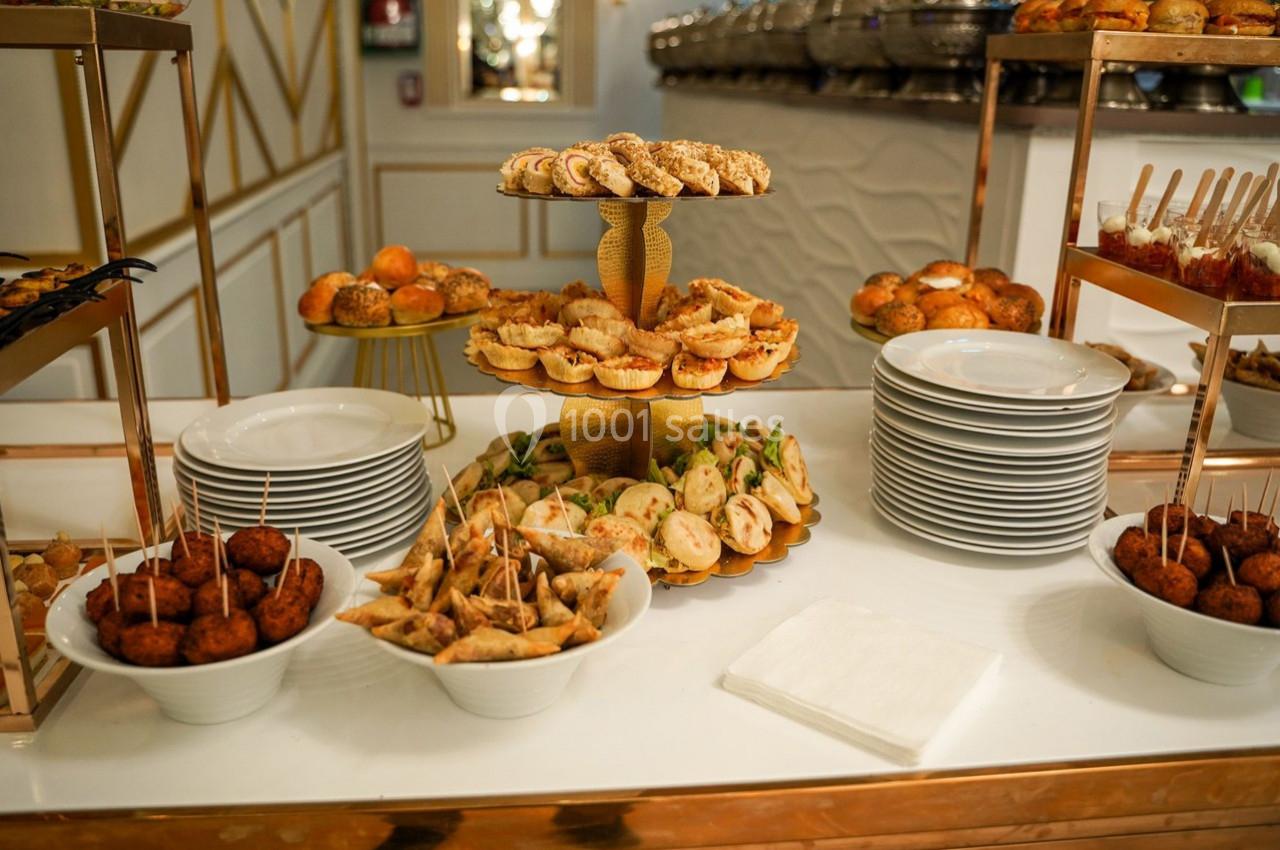 Buffet avec des assiettes empilées et une variété de bouchées salées présentées sur des plateaux et dans des bols.