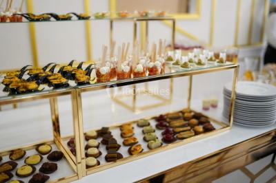 Table dressée avec une assiette blanche, un cadeau doré, une serviette beige nouée et des macarons en décoration.
