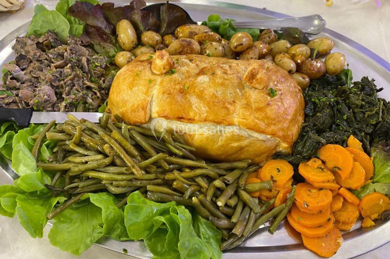 Plat composé d'un rôti en croûte, haricots verts, carottes, pommes de terre, légumes verts et champignons.