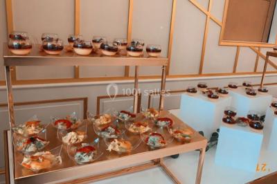 Table dressée avec une assiette blanche, un cadeau doré, une serviette beige nouée et des macarons en décoration.