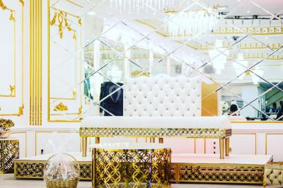 Table dressée avec une assiette blanche, un cadeau doré, une serviette beige nouée et des macarons en décoration.