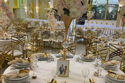 Table dressée avec une assiette blanche, un cadeau doré, une serviette beige nouée et des macarons en décoration.