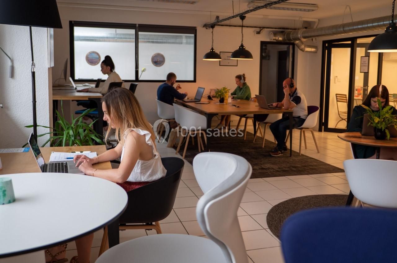 Personnes travaillant sur des ordinateurs portables dans un espace de coworking lumineux et aménagé.