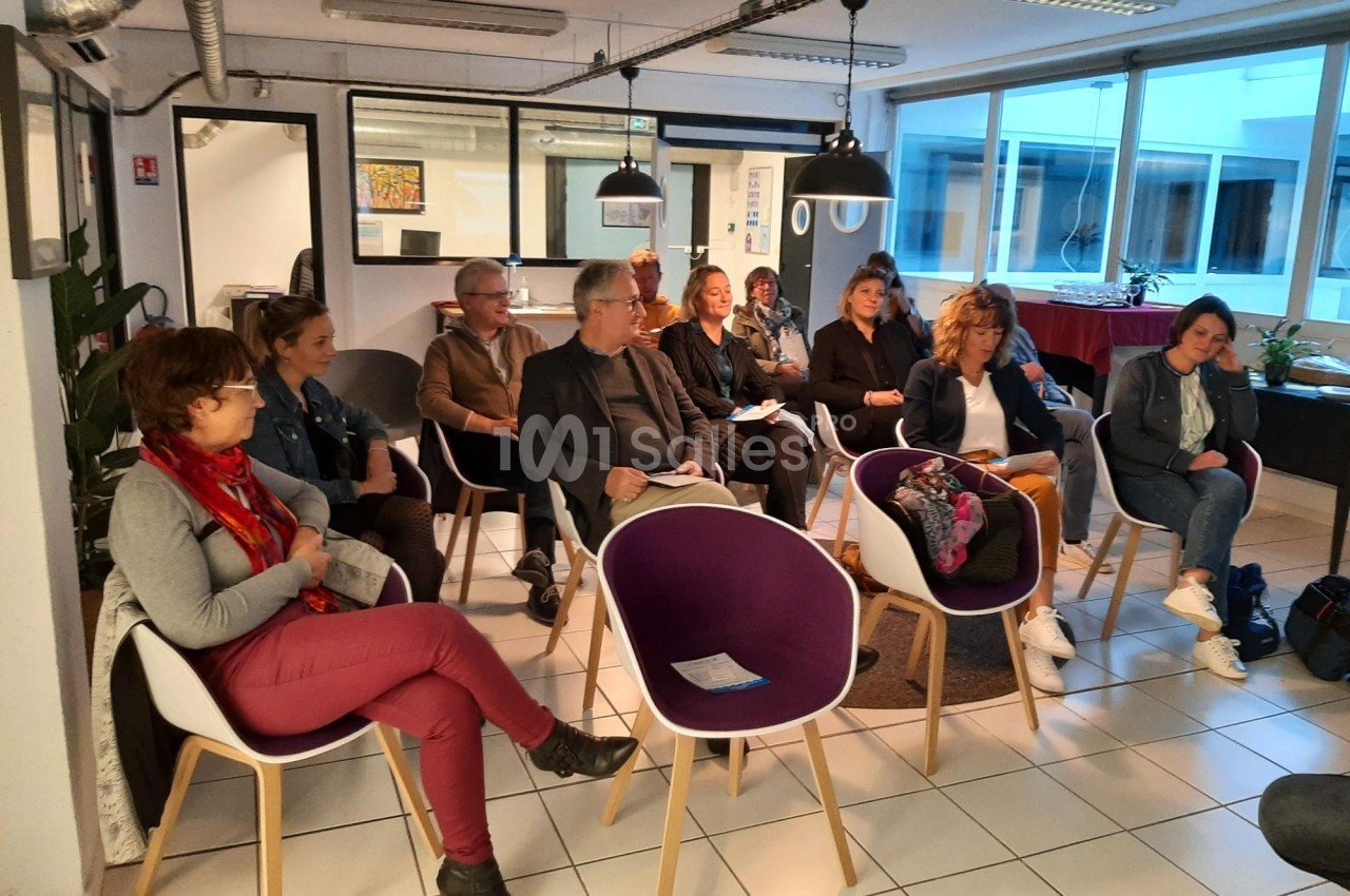 Un groupe de personnes assises dans une salle moderne, participant à une réunion ou une présentation.