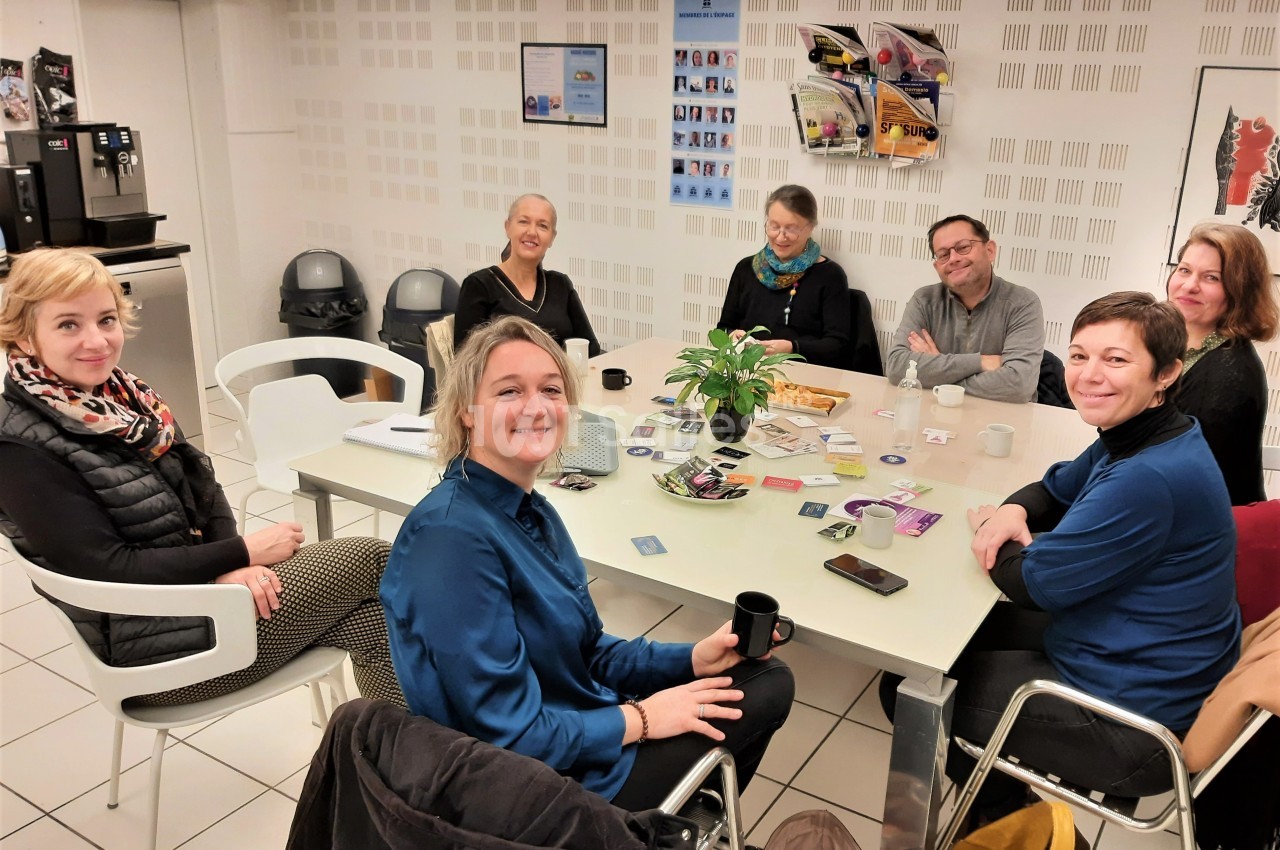 Un groupe de personnes assises autour d'une table dans une salle, discutant et partageant un moment convivial.