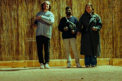 Salle lumineuse avec murs rouges, tables hautes en bois et métal, tabourets, affiches décoratives et luminaires modernes.