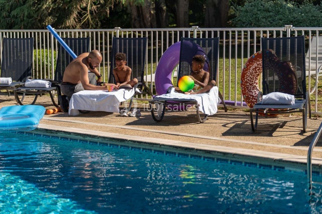 Location salle Orgeval (Yvelines) - Novotel Poissy Orgeval #16 Un homme et deux enfants assis sur des transats près d'une piscine, entourés de jouets et de serviettes.