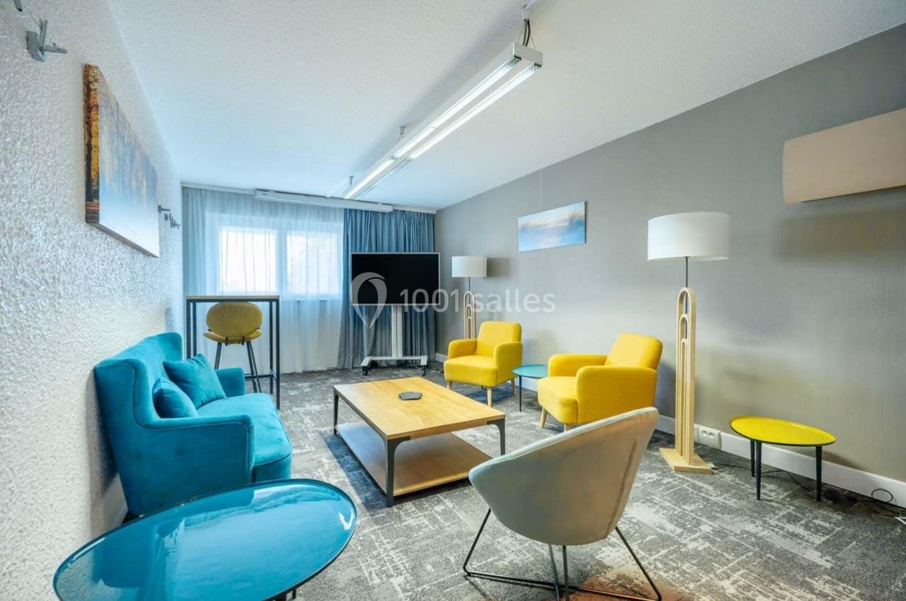 Location salle Orgeval (Yvelines) - Novotel Poissy Orgeval #32 Salle de réunion lumineuse avec fauteuils colorés, table basse en bois, téléviseur et grandes fenêtres avec rideaux.