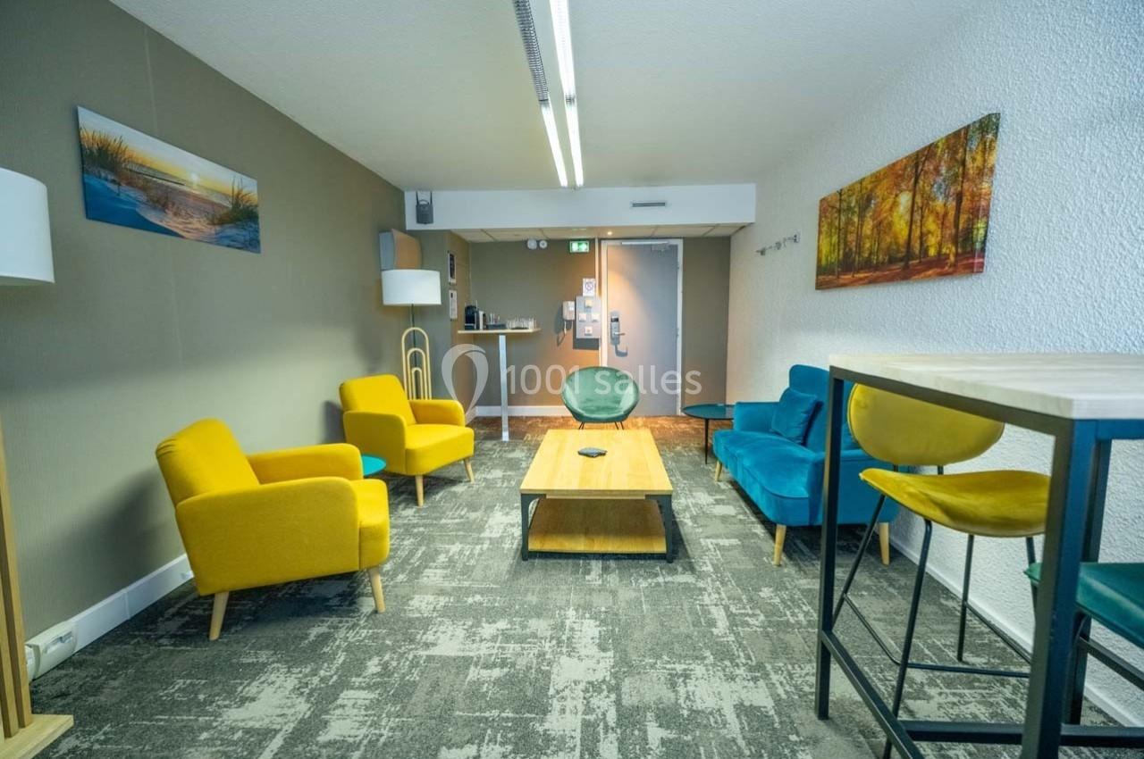 Location salle Orgeval (Yvelines) - Novotel Poissy Orgeval #33 Salle de détente avec fauteuils colorés, table basse en bois, tapis gris et décorations murales.