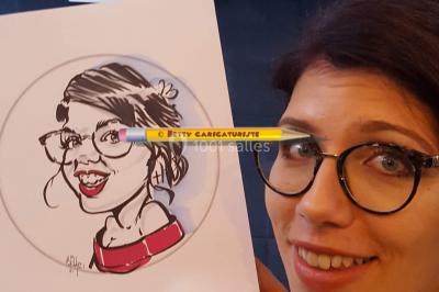 Un homme souriant tient un dessin caricatural de lui-même, réalisé avec des détails humoristiques.