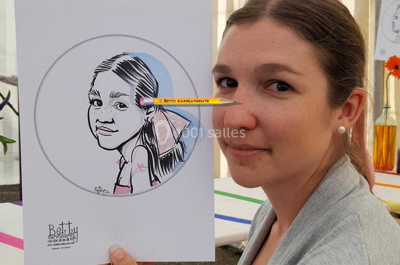 Une femme tenant un dessin caricatural d'une jeune fille, aligné avec un crayon pour un effet visuel.