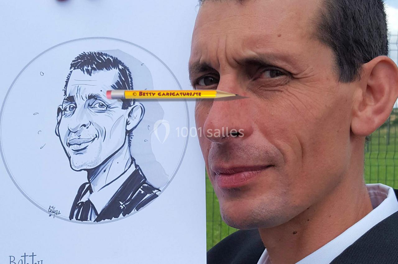 Un homme en costume tient un dessin caricatural de lui-même devant un paysage extérieur.