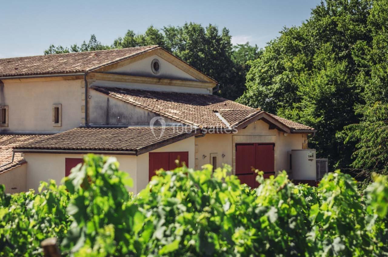 Bâtiment en pierre avec toit en tuiles entouré de vignes et de végétation sous un ciel dégagé.