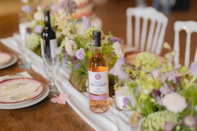 Miniature Location salle Paillet (Gironde) - Château Sainte Catherine #25 Bouteille de vin rosé posée sur une table décorée de fleurs, entourée de verres et d'assiettes.