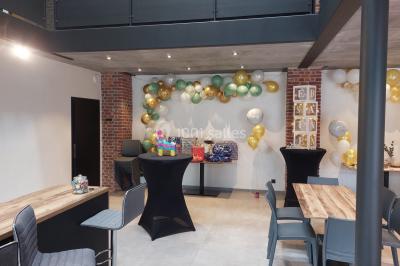 Structure gonflable colorée en forme d'arche, installée sur une cour pavée devant des maisons en briques.