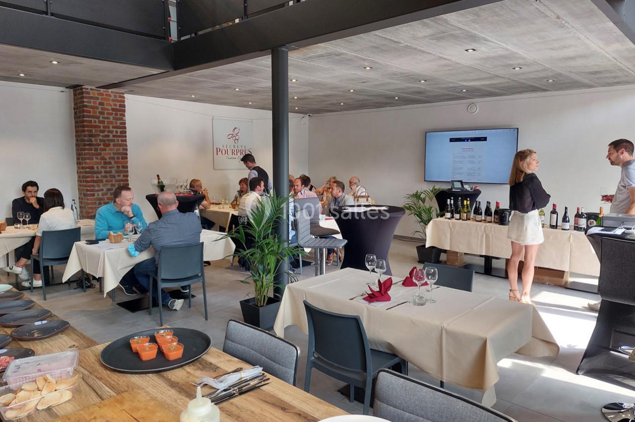 Des personnes dînent et discutent dans un restaurant lumineux avec des tables dressées et des bouteilles exposées.