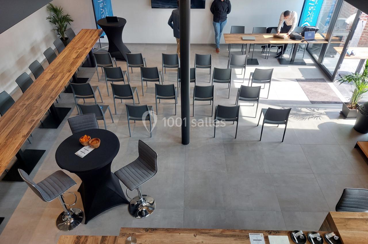 Salle de réunion moderne avec chaises disposées en rangées, tables hautes et grandes baies vitrées laissant entrer la…