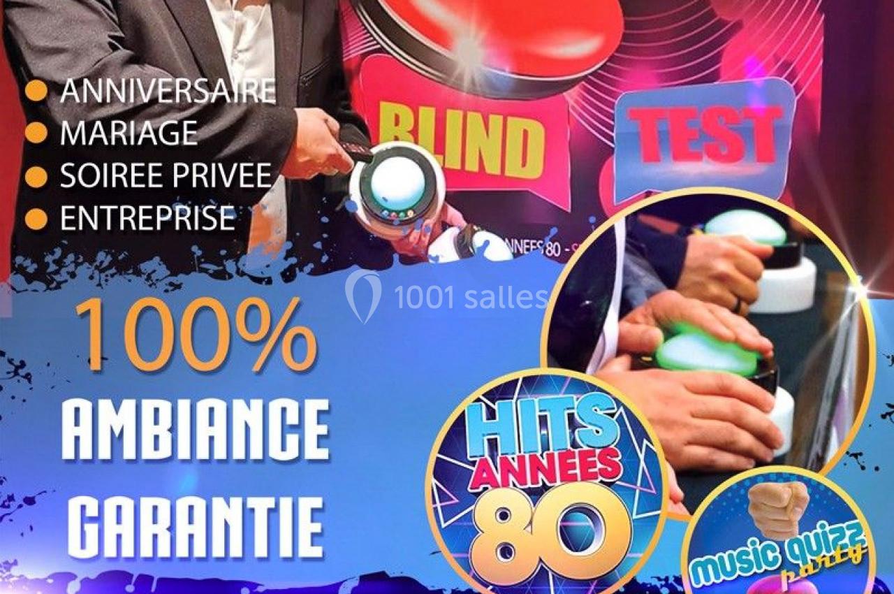 Un homme tenant un buzzer devant une affiche promotionnelle pour un blind test musical.
