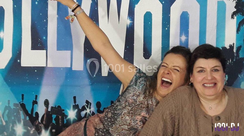 Deux femmes souriantes posent devant un décor évoquant une ambiance festive et hollywoodienne.