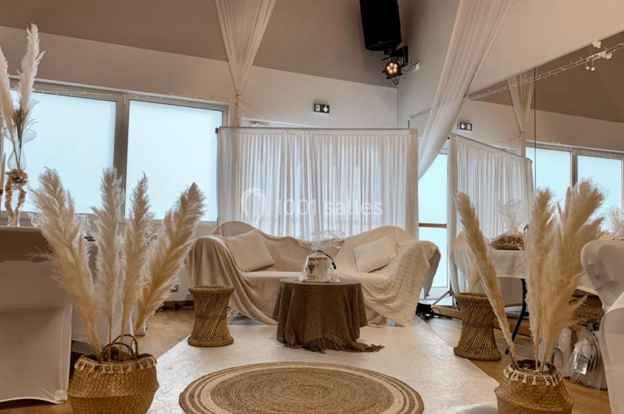 Espace lumineux décoré de voilages blancs, mobilier clair et plantes de pampa dans des paniers tressés.