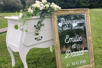 Miniature Panneau de bienvenue MIROIR Commode blanche avec fleurs et miroir doré affichant un message de bienvenue pour un mariage en extérieur.