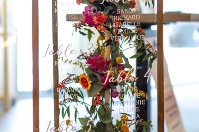 Miniature Plan de Table COLOR Commode blanche avec fleurs et miroir doré affichant un message de bienvenue pour un mariage en extérieur.