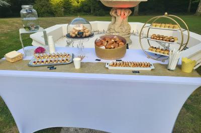 Table élégamment dressée avec nappes blanches, chaises assorties, chandeliers, fleurs roses et couverts dorés.
