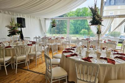Table élégamment dressée avec nappes blanches, chaises assorties, chandeliers, fleurs roses et couverts dorés.