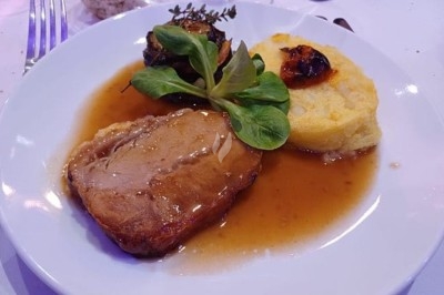 Table élégamment dressée avec nappes blanches, chaises assorties, chandeliers, fleurs roses et couverts dorés.