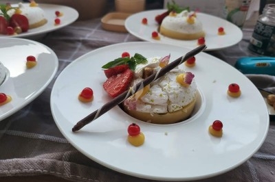 Table élégamment dressée avec nappes blanches, chaises assorties, chandeliers, fleurs roses et couverts dorés.