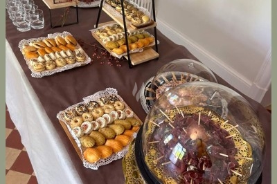 Table élégamment dressée avec nappes blanches, chaises assorties, chandeliers, fleurs roses et couverts dorés.
