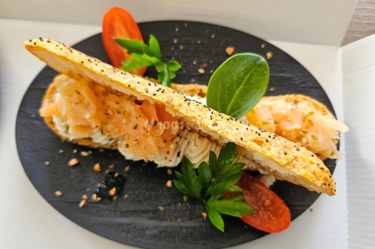 Tranches de saumon fumé sur pain croustillant avec fromage frais, décorées de tomates cerises et herbes fraîches.