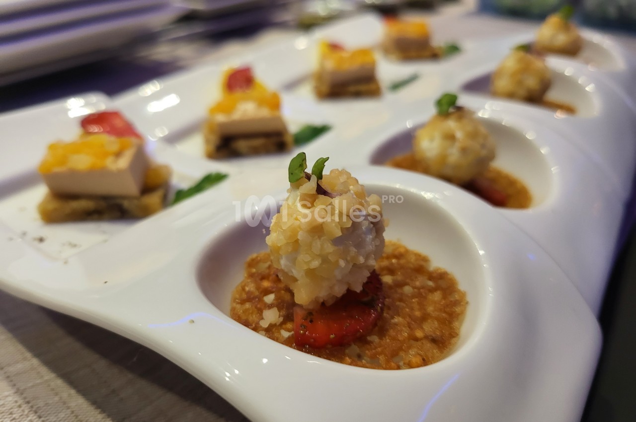 Assortiment de bouchées gastronomiques présentées sur un plateau, avec des ingrédients variés et une présentation soignée.