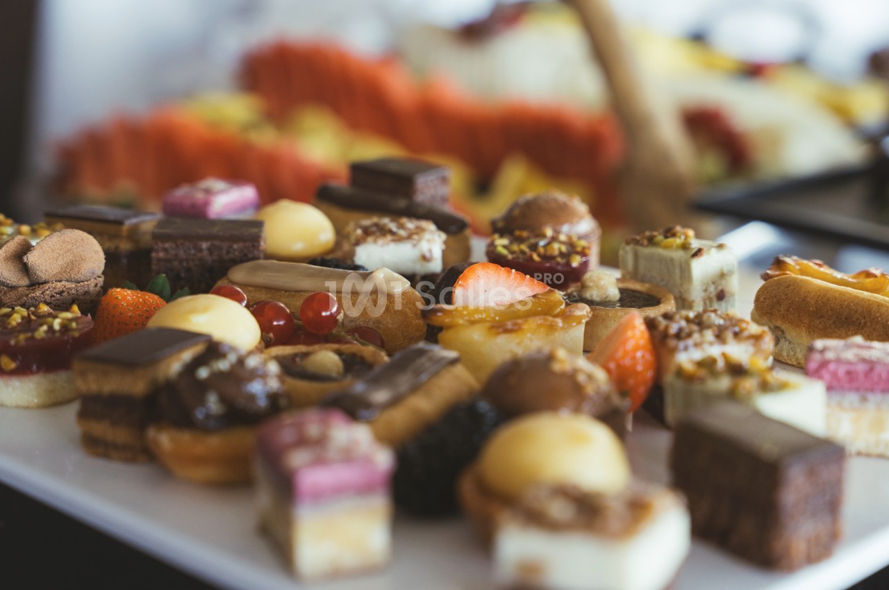 Plateau de petits desserts variés, incluant des pâtisseries, fruits et chocolats, disposés sur une table.