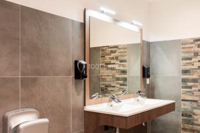 Radiateur sèche-serviettes blanc fixé sur un mur bleu, près d'un lavabo et d'étagères ouvertes.