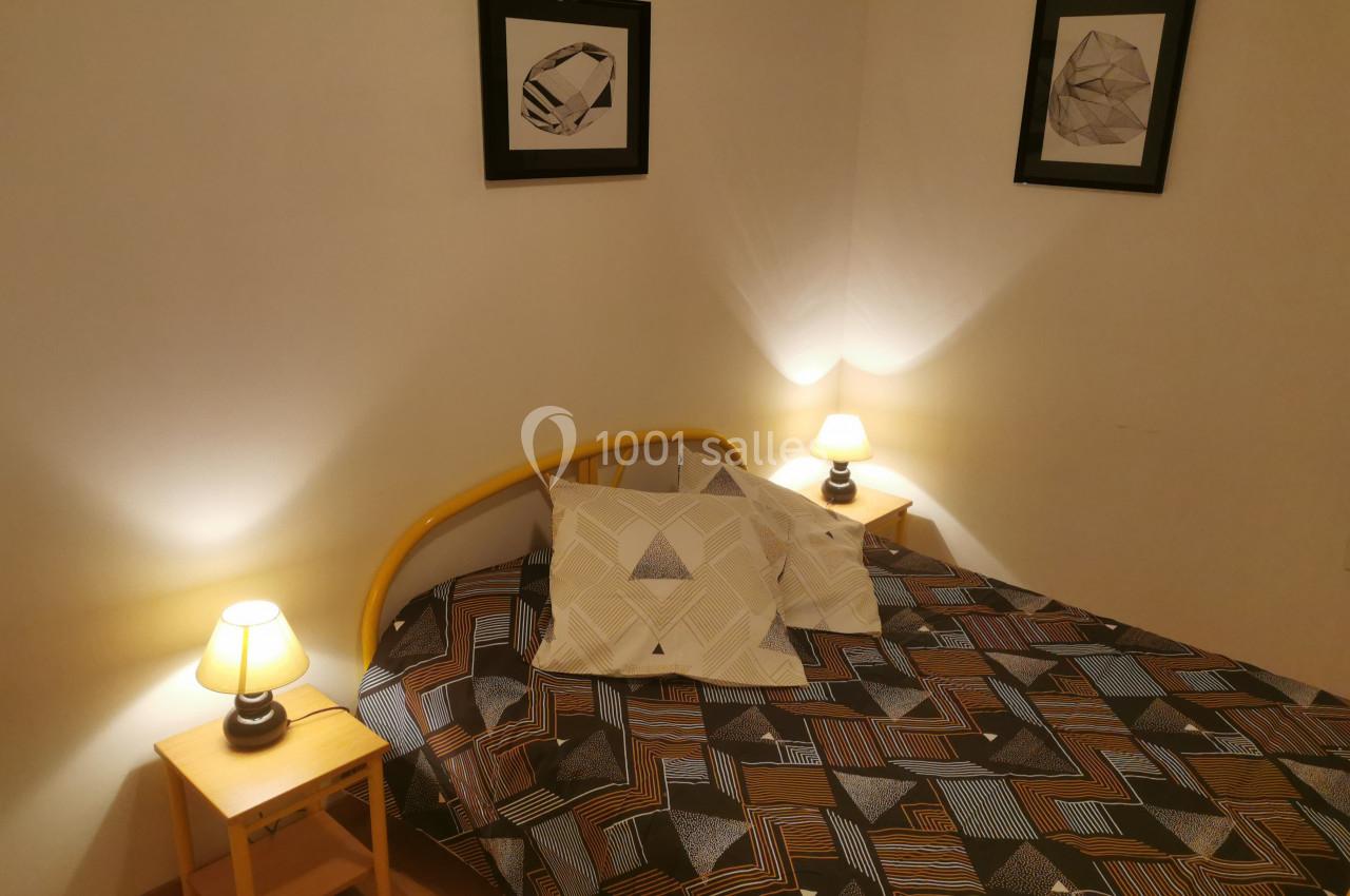 Location salle Gouville-sur-Mer (Manche) - Le Village du Phare #31 Lit double avec housse géométrique, encadré par deux tables de chevet avec lampes allumées, dans une chambre sobre.