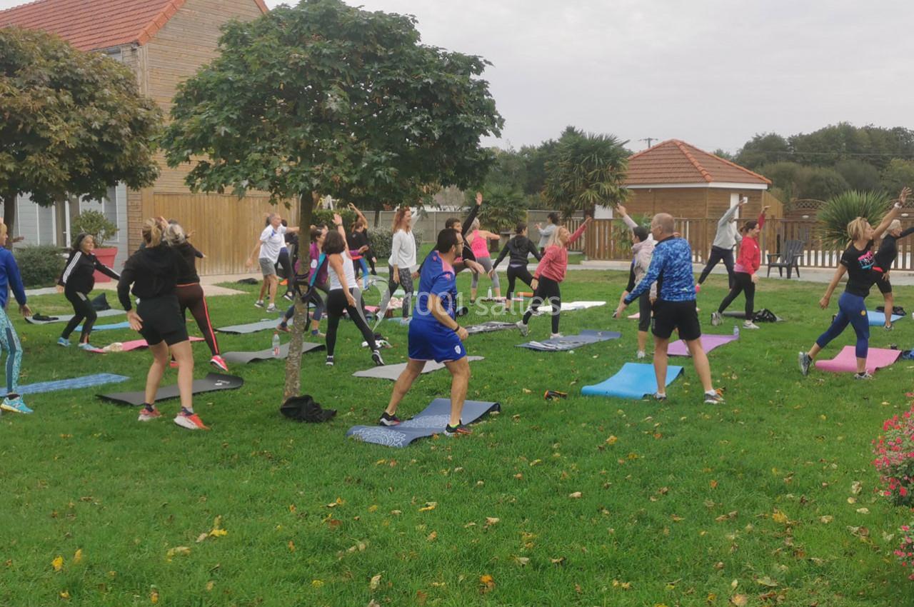 Location salle Gouville-sur-Mer (Manche) - Le Village du Phare #15 Groupe de personnes pratiquant des exercices physiques en plein air sur des tapis dans un espace vert.