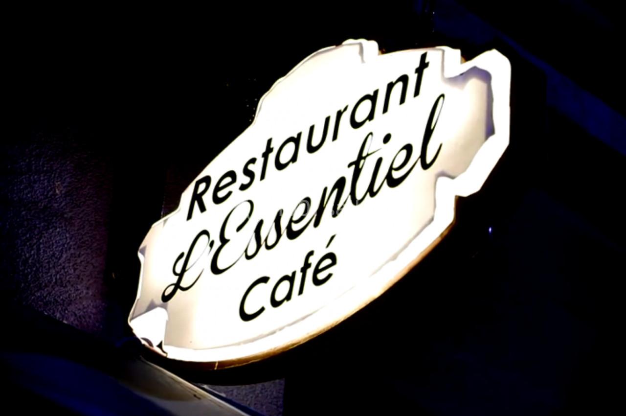 Enseigne lumineuse indiquant ’Restaurant L'Essentiel Café’ sur une façade sombre.