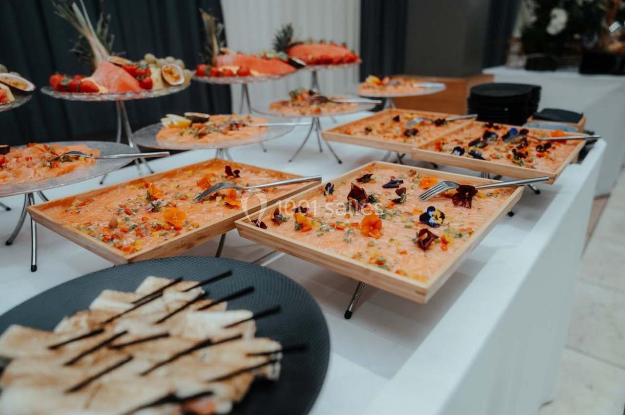 Plateaux de saumon mariné garnis de fleurs comestibles, accompagnés de pain grillé sur une table de buffet.