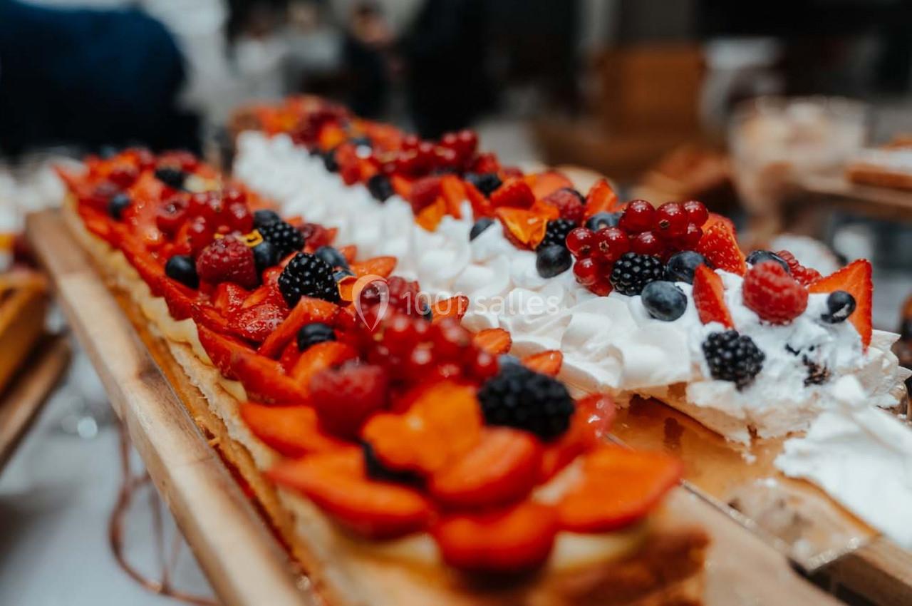 Tartes garnies de fraises, mûres, groseilles et crème chantilly, présentées sur une table en bois.