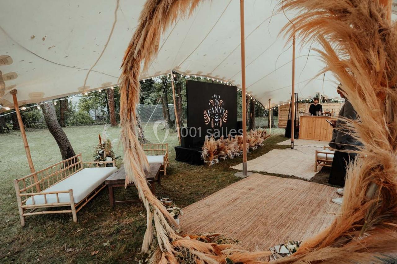 Intérieur d'une tente décorée avec des meubles en bois, des plantes séchées et un panneau noir orné de motifs.
