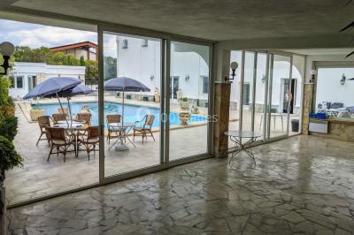 Miniature Location salle Lambesc (Bouches-du-Rhône) - Villa Maya Provence #24 Salle lumineuse avec tables rectangulaires, chaises noires et verrerie suspendue, donnant sur de grandes fenêtres.