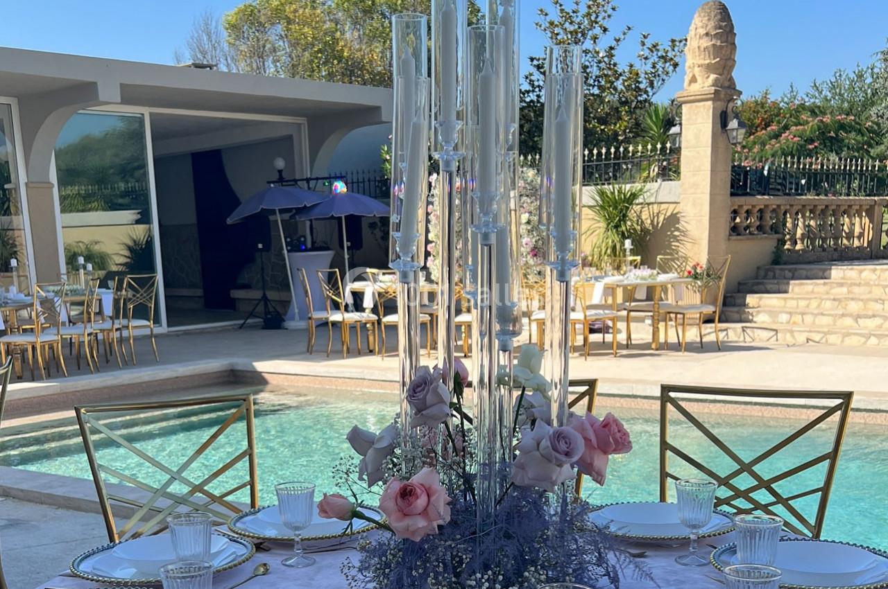 Centre de table floral avec roses et bougies, disposé près d'une piscine dans un cadre extérieur élégant.