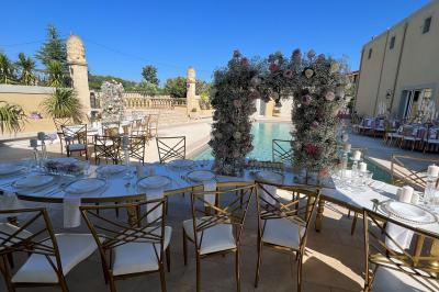 Miniature Location salle Lambesc (Bouches-du-Rhône) - Villa Maya Provence #2 Salle lumineuse avec tables rectangulaires, chaises noires et verrerie suspendue, donnant sur de grandes fenêtres.