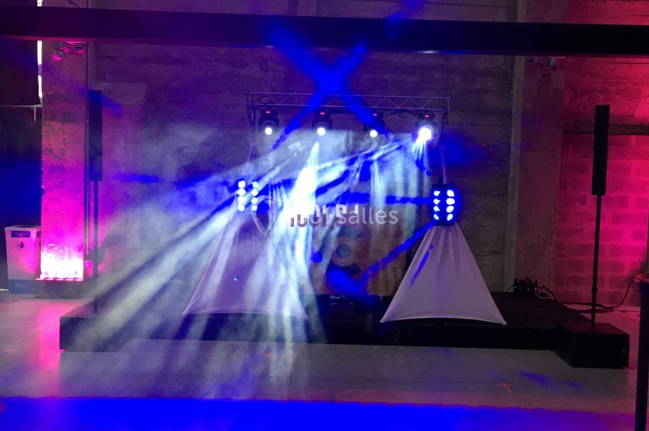 Jeux de lumière colorés projetés sur une scène dans un espace intérieur avec murs en béton.