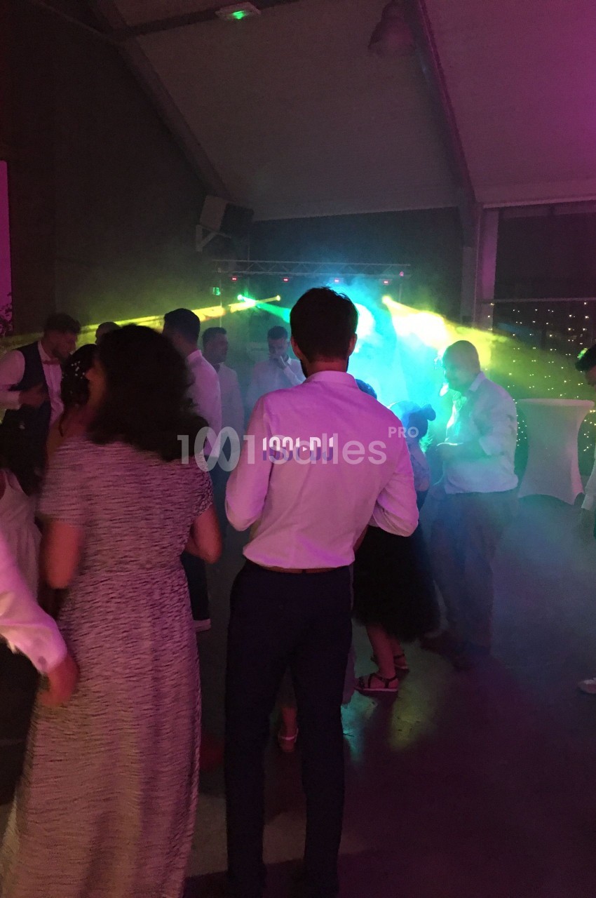 Des personnes dansent sous des lumières colorées dans une ambiance festive en intérieur.