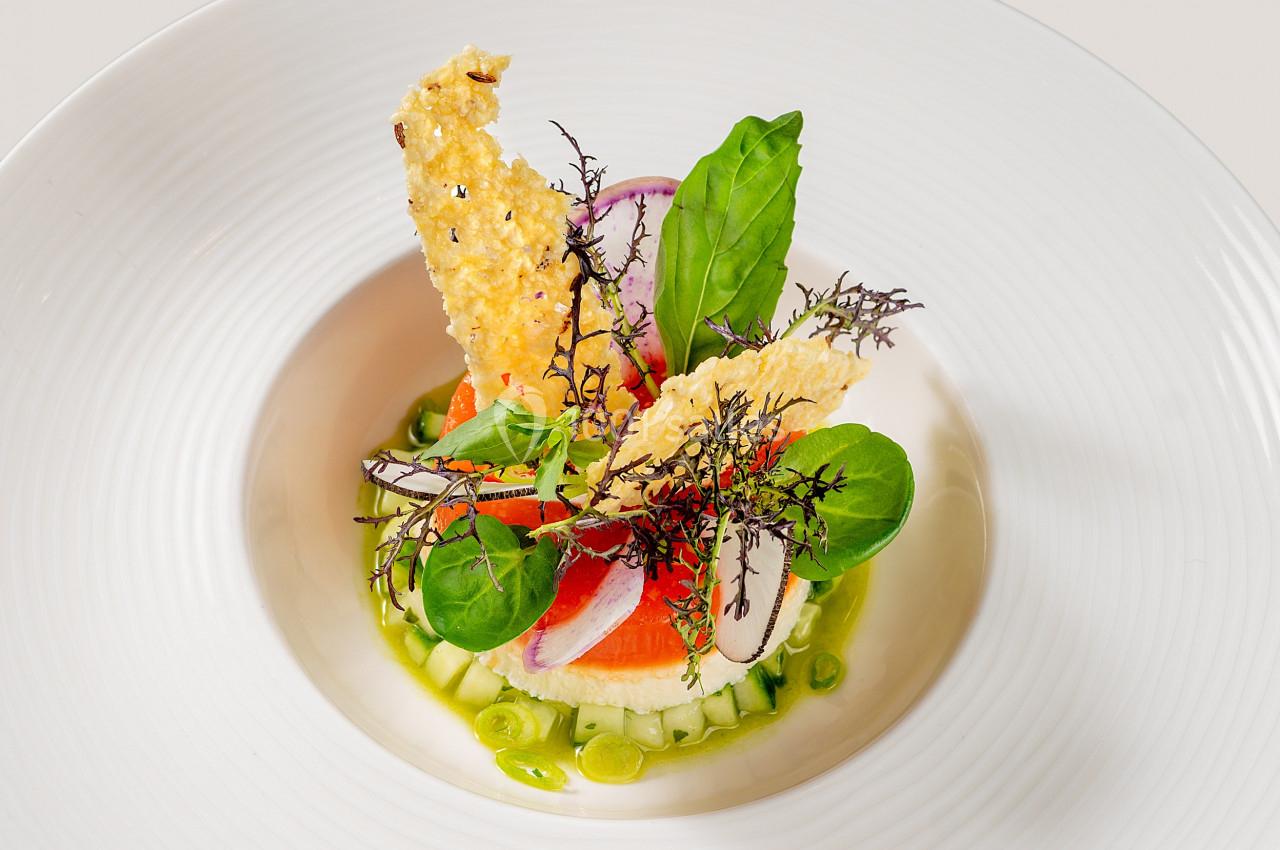 Assiette gastronomique composée de légumes frais, herbes, crackers croustillants et sauce verte.