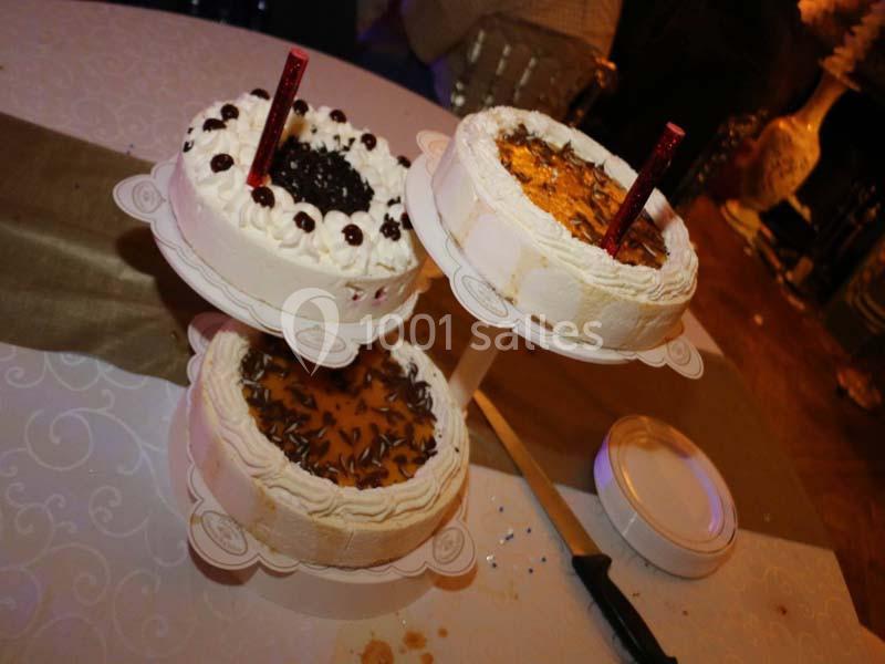 Trois gâteaux décorés de crème et garnitures variées, présentés sur un présentoir à étages lors d'un événement.